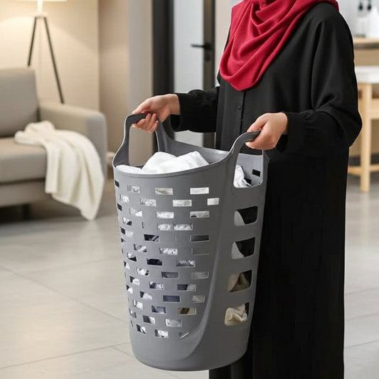 Woman holding a gray laundry basket filled with clothes in a modern living room.