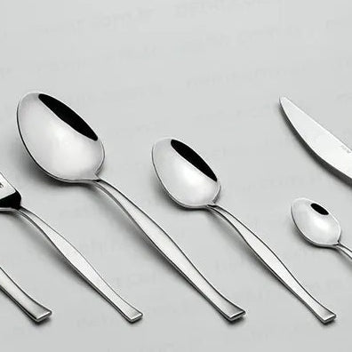 Set of silver cutlery including forks, knives, and spoons on a light gray background