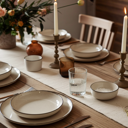 Dining table set with plates, glasses, and candles in a warm indoor setting.